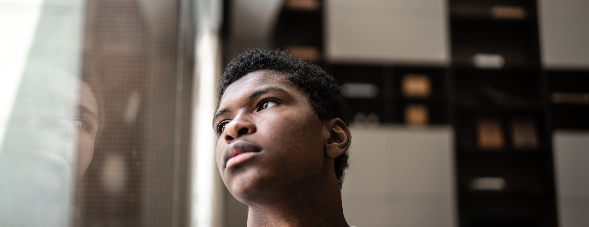 Depressed teen boy looking out a window