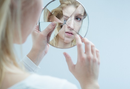 A woman looking in a broken mirror.