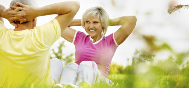older couple doing sit-ups outside