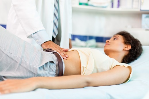 Doctor examining lower abdomen of female patient.