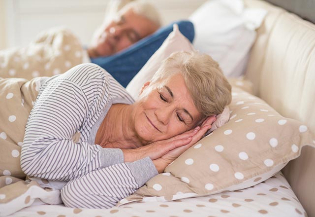 A senior couple asleep in bed.