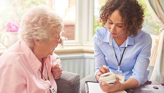 A caregiver assists a senior woman.