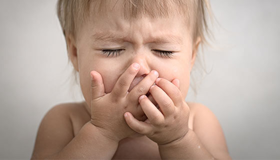 small child covers mouth