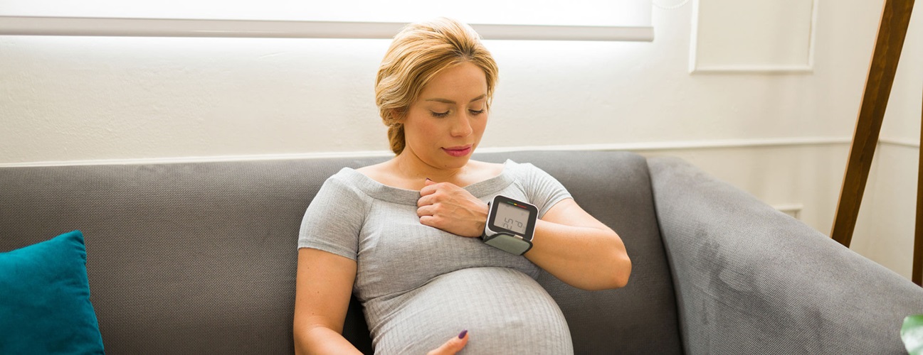 pregnant person with blood pressure cuff on wrist