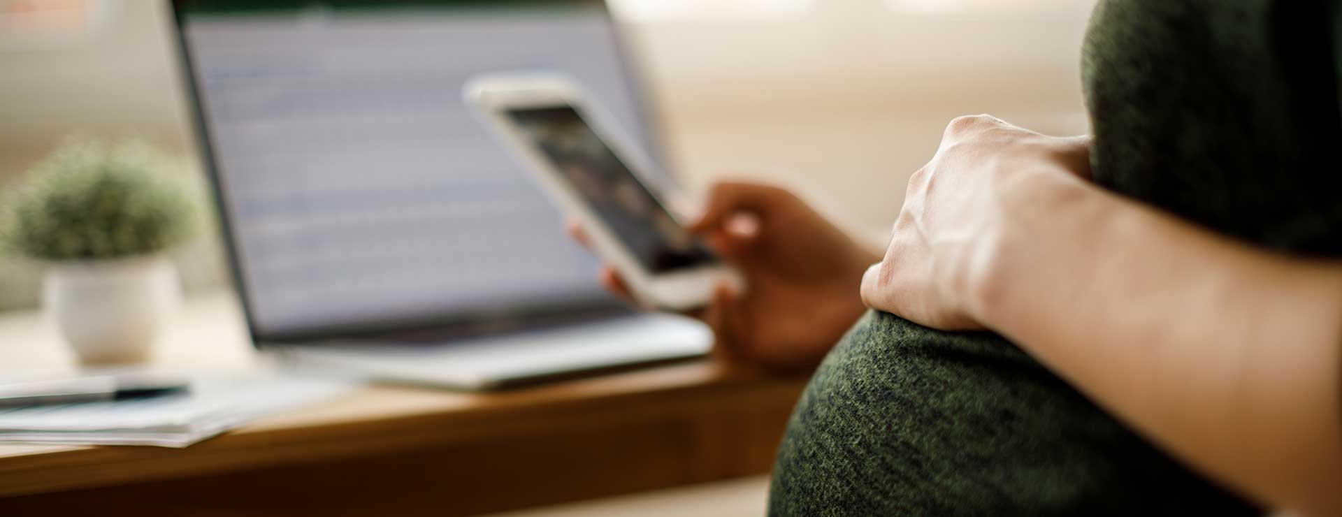 Pregnant woman sits at her desk with a mobile phone