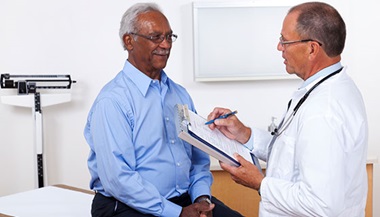 A senior man talks with his doctor during a medical exam.