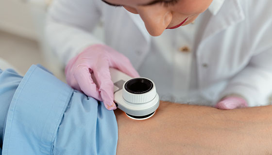 Dermatologist uses her dermatoscope to examine a patient's arm