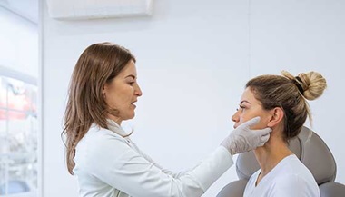Dermatologist examines a patient's face for signs of rosacea