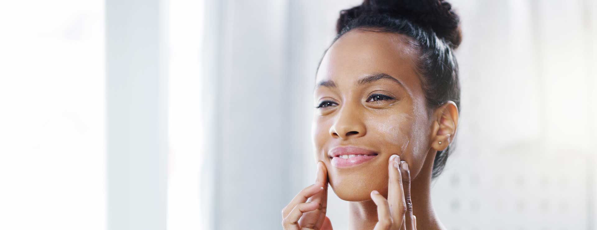 young woman applying lotion to face