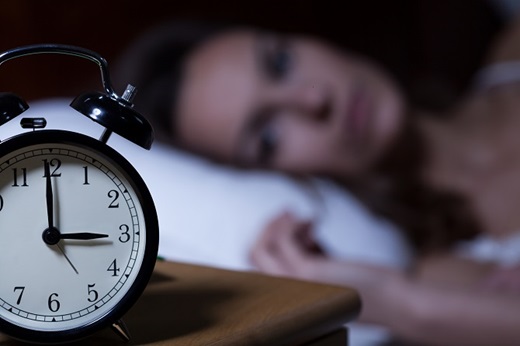 Woman stares at her alarm clock in the middle of the night.