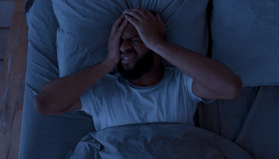 Man holding his head as he has a nightmare