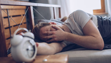Sleeping man disturbed by his alarm clock