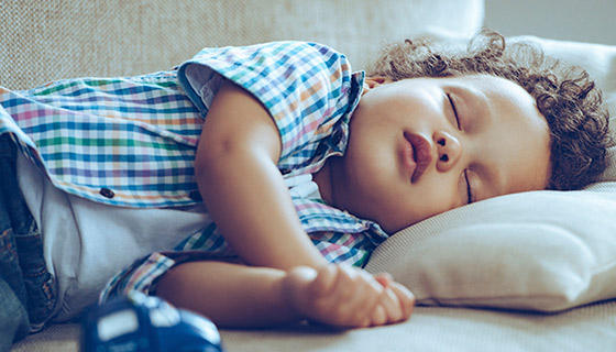 Toddler fast asleep on a sofa.