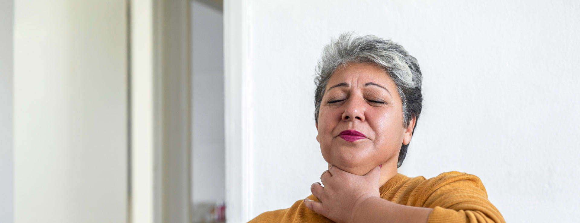 Woman holding her throat while she experiences GERD