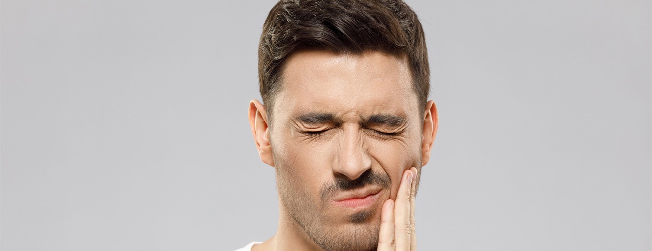 Man dealing with discomfort from senstive teeth. 