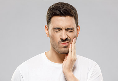 Man dealing with discomfort from sensitive teeth.