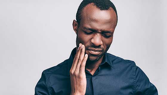 man holding his jaw in pain