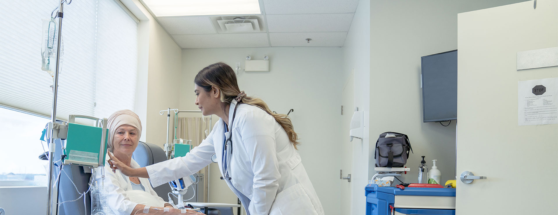 A clinician using a chemotherapy drip next to a patient.