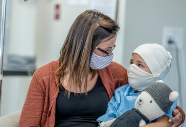 Young, masked oncology patient with masked parent
