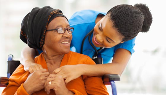 Elderly surgery patient in a wheelchair being directed by a nurse