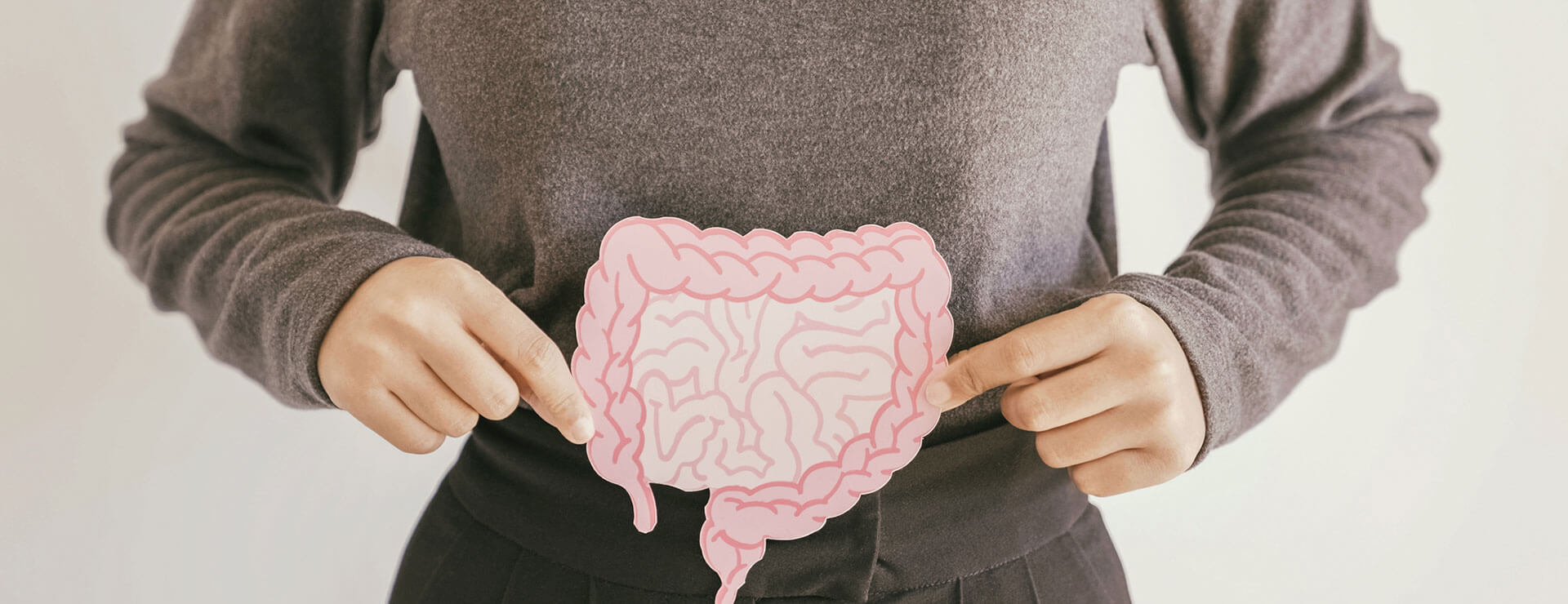 person holds drawing of colon and intestinal tract over abdomen