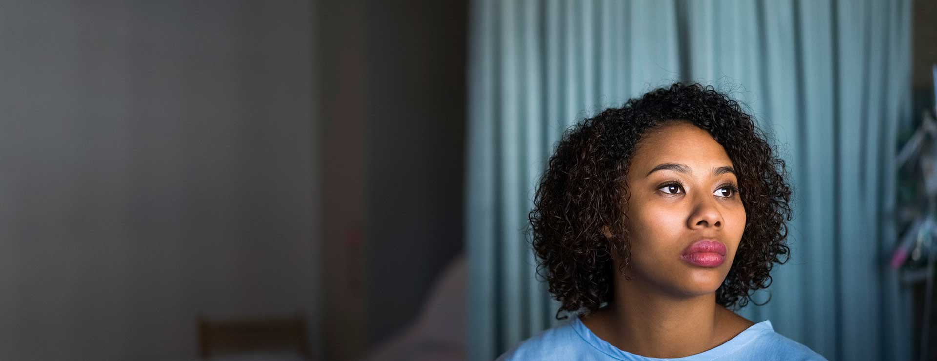 A female patient sits on a hospital bed.
