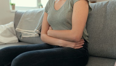 Woman with abdominal pain hugging her stomach