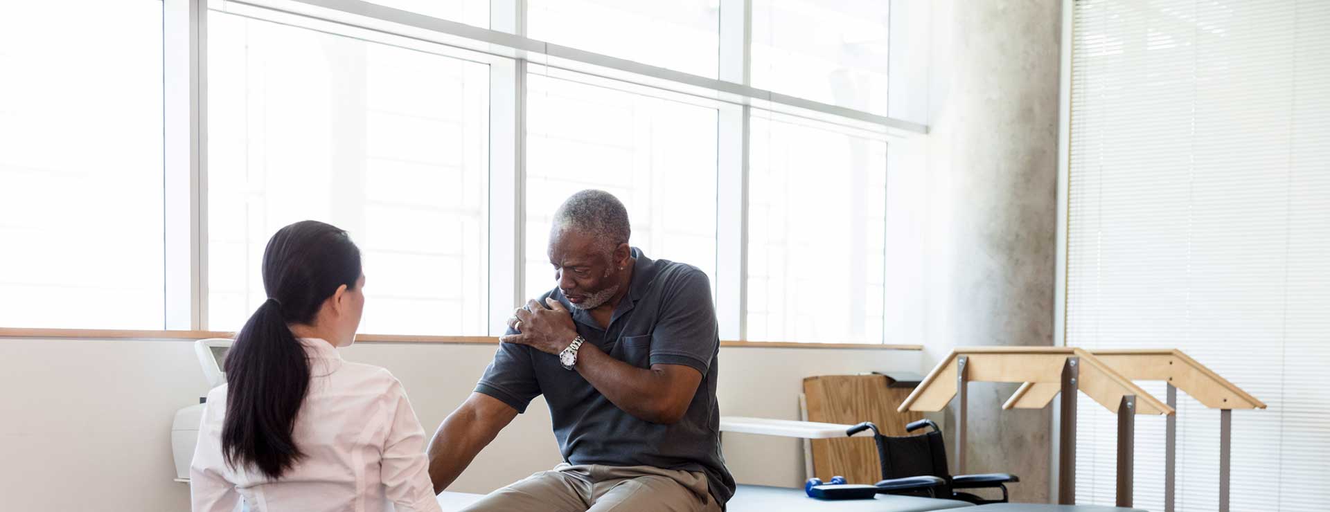 Doctor examining a patient's range of motion as he rotates his arm.
