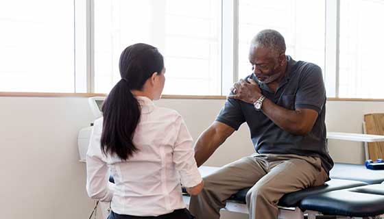 Doctor examining a patient's range of motion as he rotates his arm.