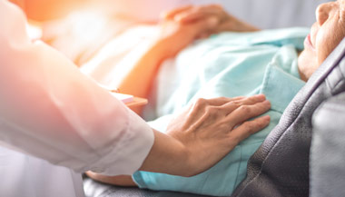 Healthcare worker comforting patient in hospital bed