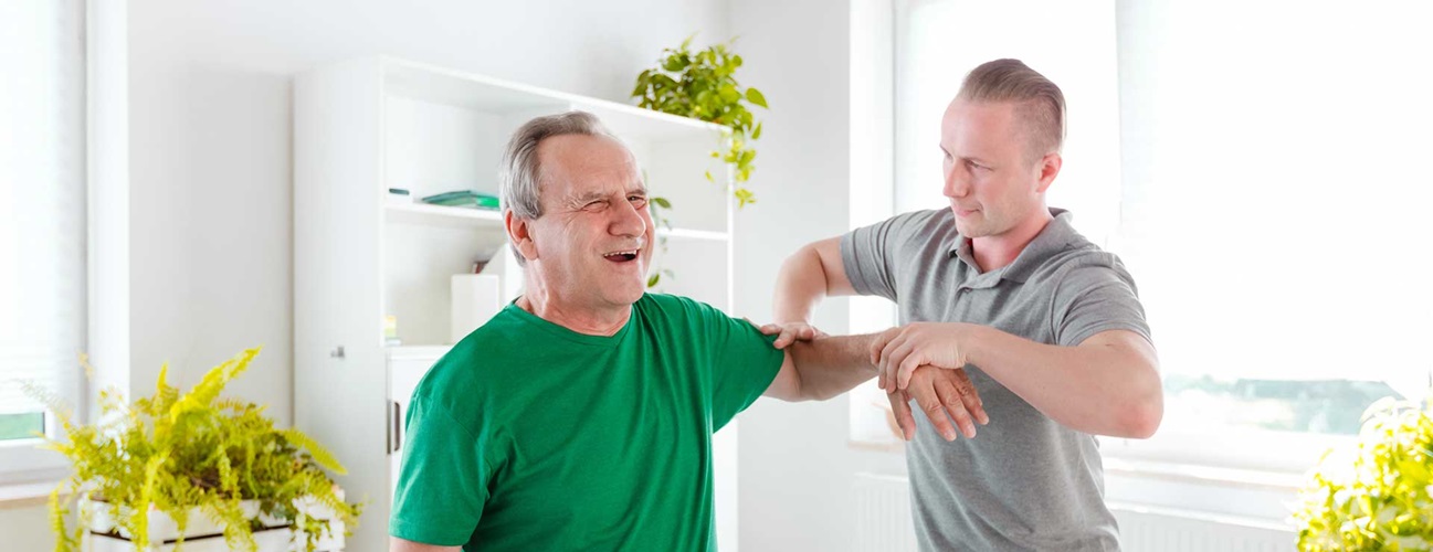 Physical therapist examining senior man's shoulder problem
