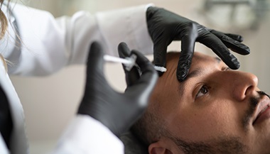 A man receives a botulinum toxin injection to his forehead.