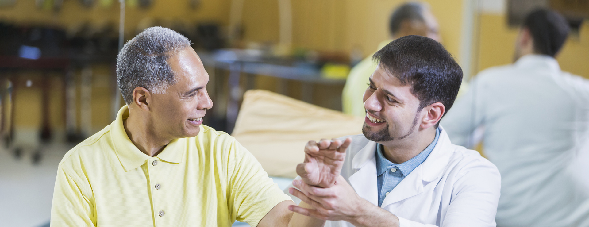 A doctor examines an older male patient's wrist.