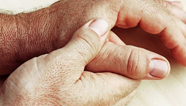 A person suffering with Dupuytren's contracture rubs their hands in pain.