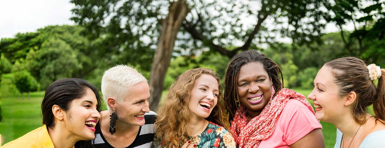 A group of female plastic and reconstructive surgery patients smile together outdoors.