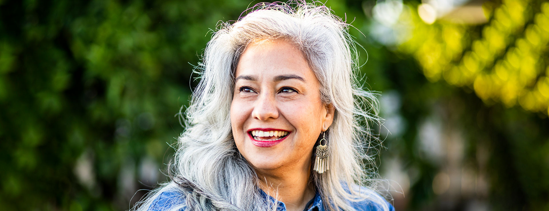 A mature woman stands outside, smiling broadly.