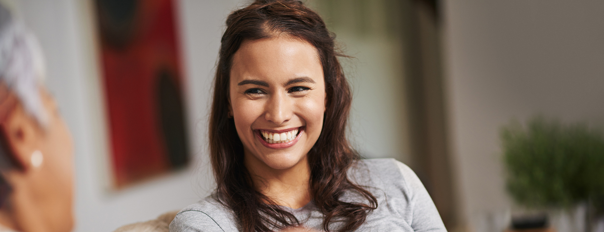 A young woman smiles while talking to her older friend following nose reshaping surgery.