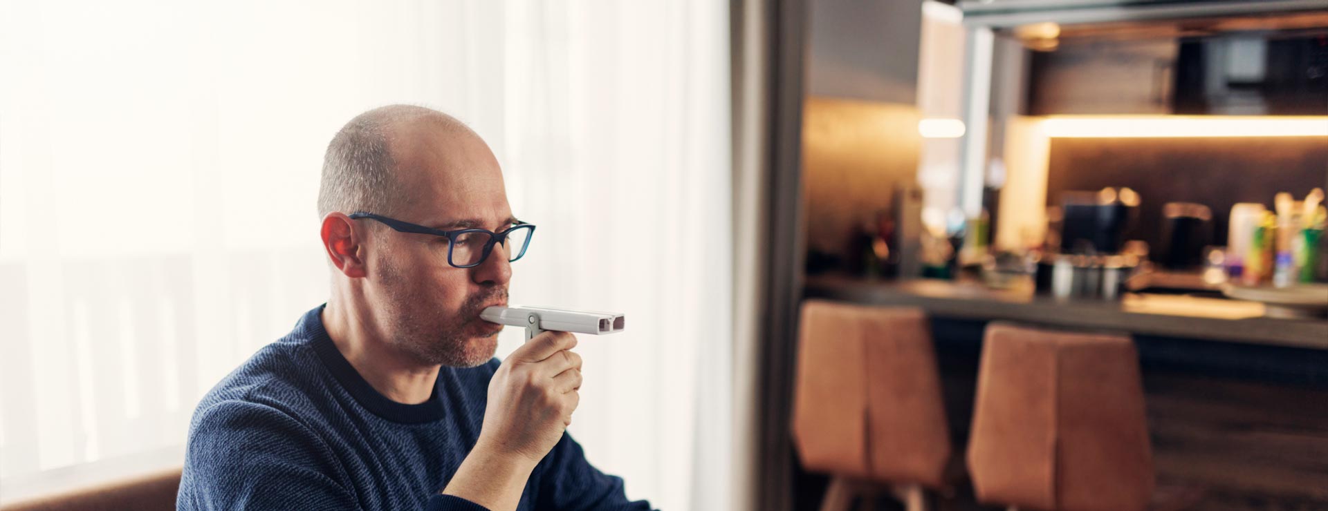 Man using peak flow meter to check his lungs