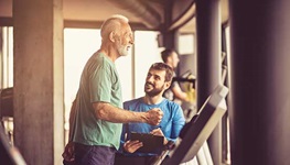 older man with trainer doing cardio