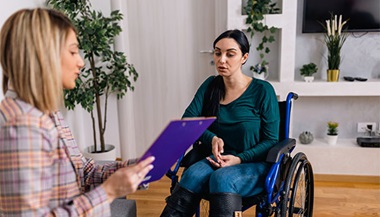 A Vocational counselor talking with a woman in a wheelchair.