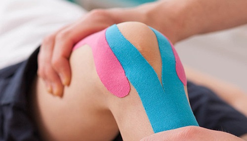 Blue and pink bandages stretching vertically over a knee