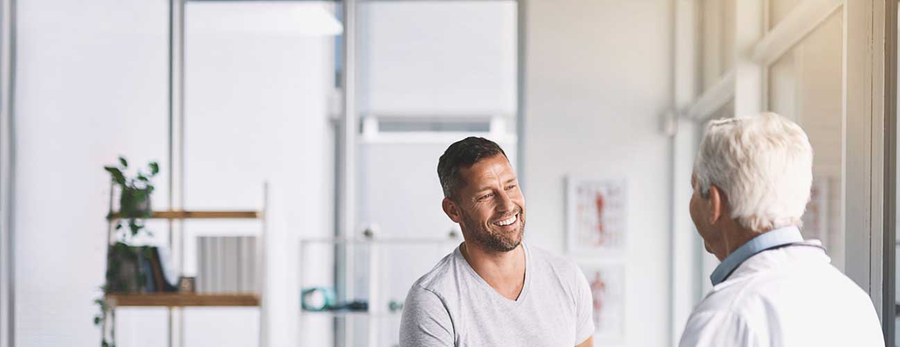 Man speaks with his urologist during an appointment in a sunny office