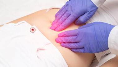 Doctor examining stomach area of patient with light pressure