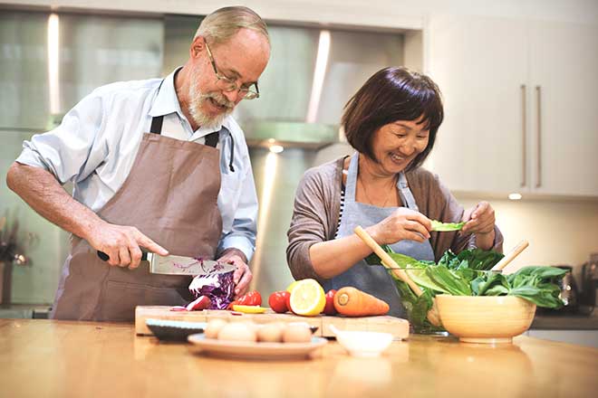 Two seniors chopping vegetables