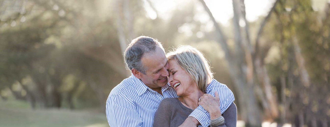 happy older couple hugging in a park