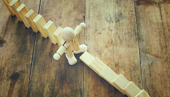 Wooden figure stopping falling dominos