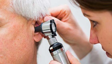 Doctor checking an old patient's ear