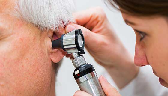Doctor checking an old patient's ear