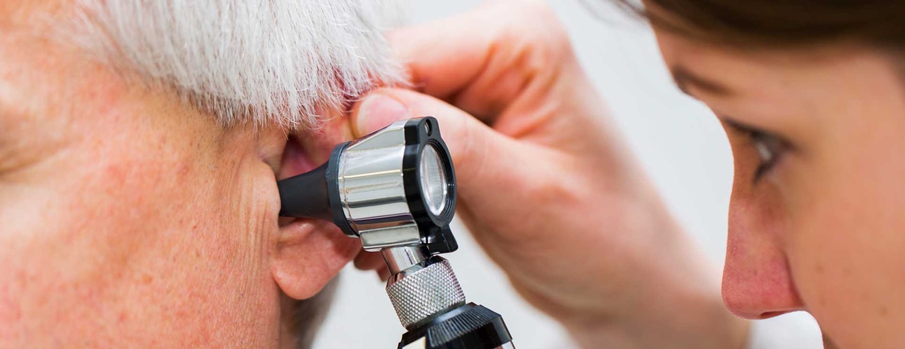 Woman doctor examining an elderly man's ear
