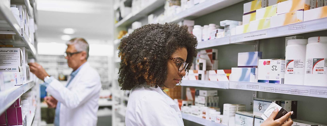 Two pharmacists looking at medications on the pharmacy shelf